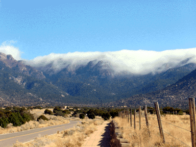 This is a photograph of a cloudspill which is clouds spilling over and hugging the Bear Canyon Mountain Ridge in Elena Gallegos Park in Northwest Albuquerque. 